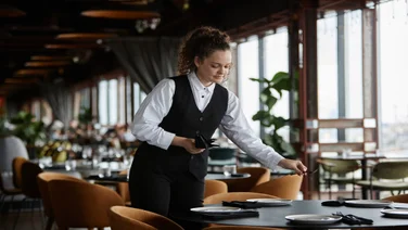 A restaurant worker lays a table.