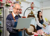 A florist owner with a laptop, using the startups business toolkit.