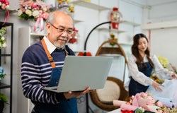 A florist owner with a laptop, using the startups business toolkit.
