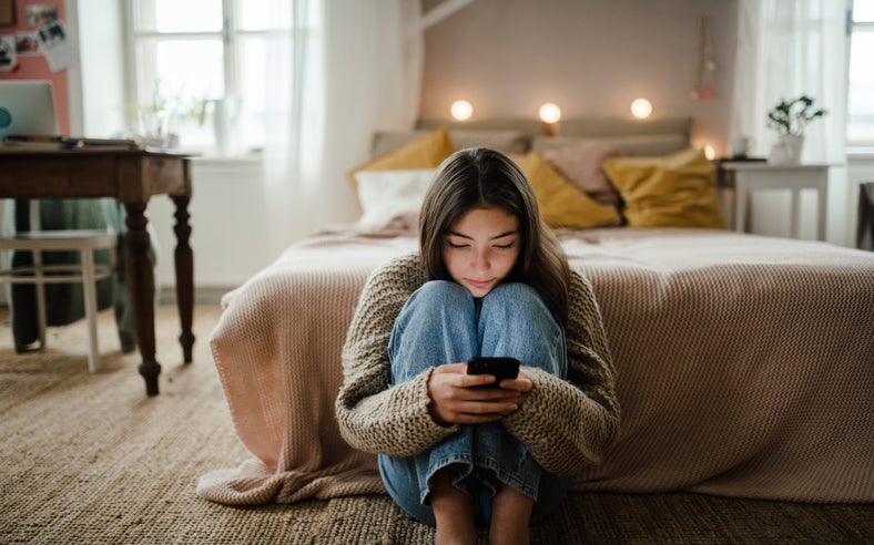 teenager using her phone in her bedroom